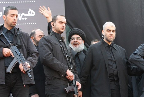 The head of Lebanon's militant Shiite Muslim movement Hezbollah, Hassan Nasrallah is surrounded by security guards as he greets the audience after giving a speech during a massive Shiite Muslim commemoration in southern Beirut on November 14, 2013. Nasrallah vowed to keep his forces in Syria where they are fighting alongside President Bashar al-Assad's regime, during his rare public speech.   AFP PHOTO/ STR